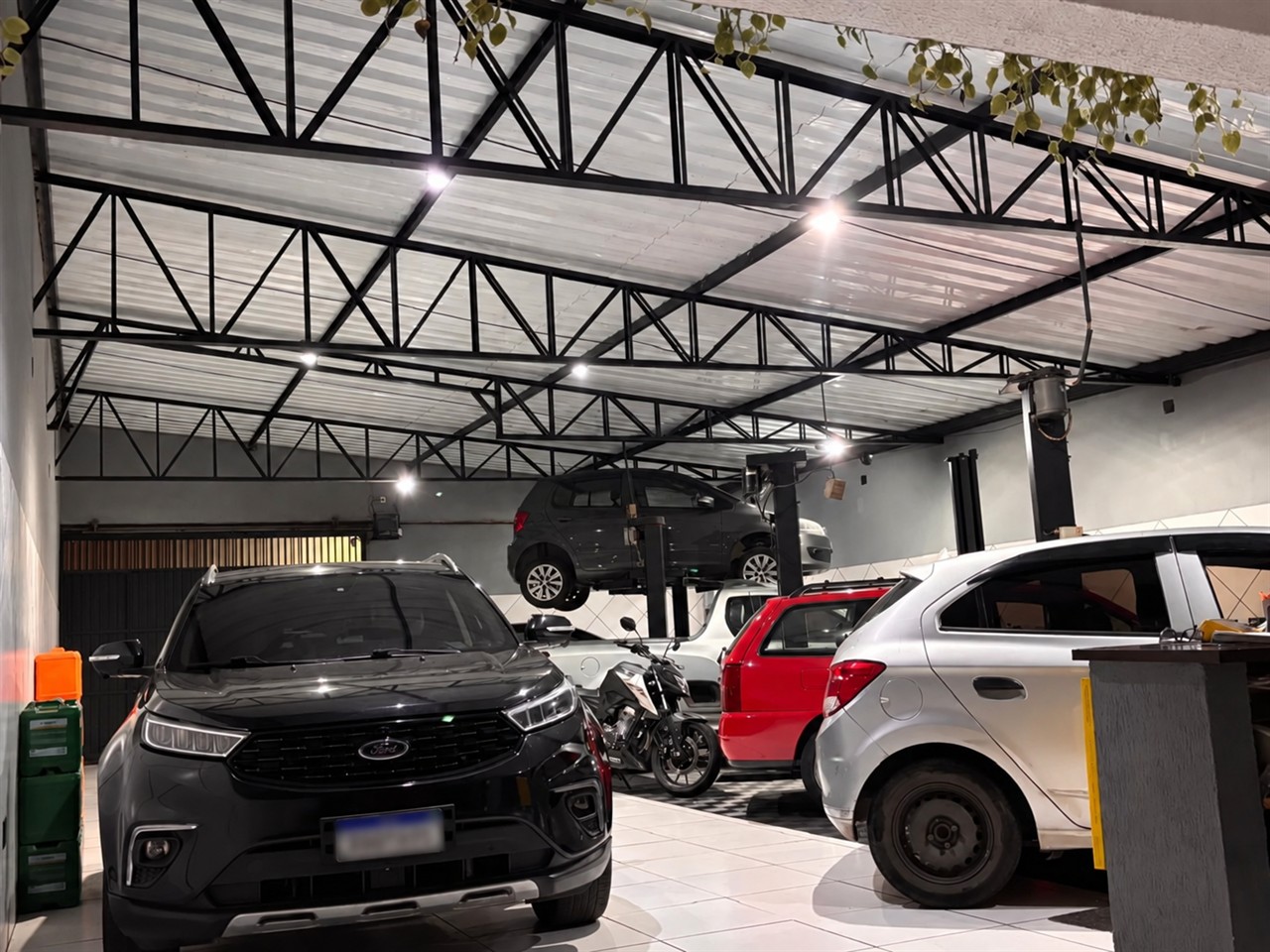 Interior da Nazaki Auto Center, com veículos em manutenção e um carro no elevador